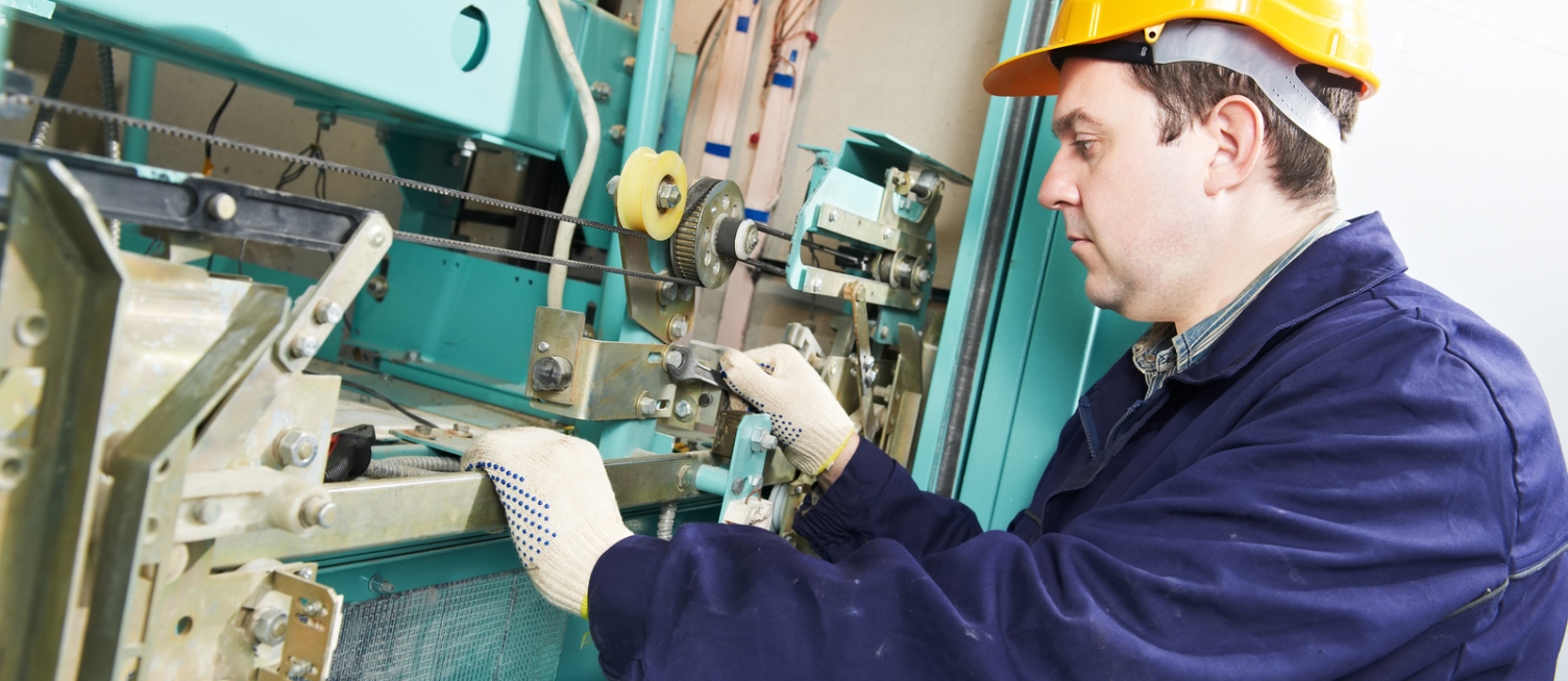 One machinist worker at work adjusting elevator mechanism of lift with spanner