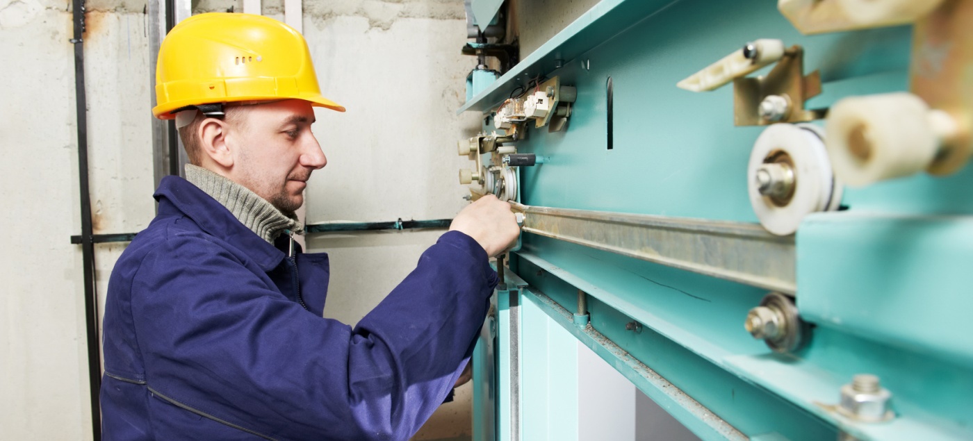 One machinist worker at work adjusting elevator mechanism of lift with spanner